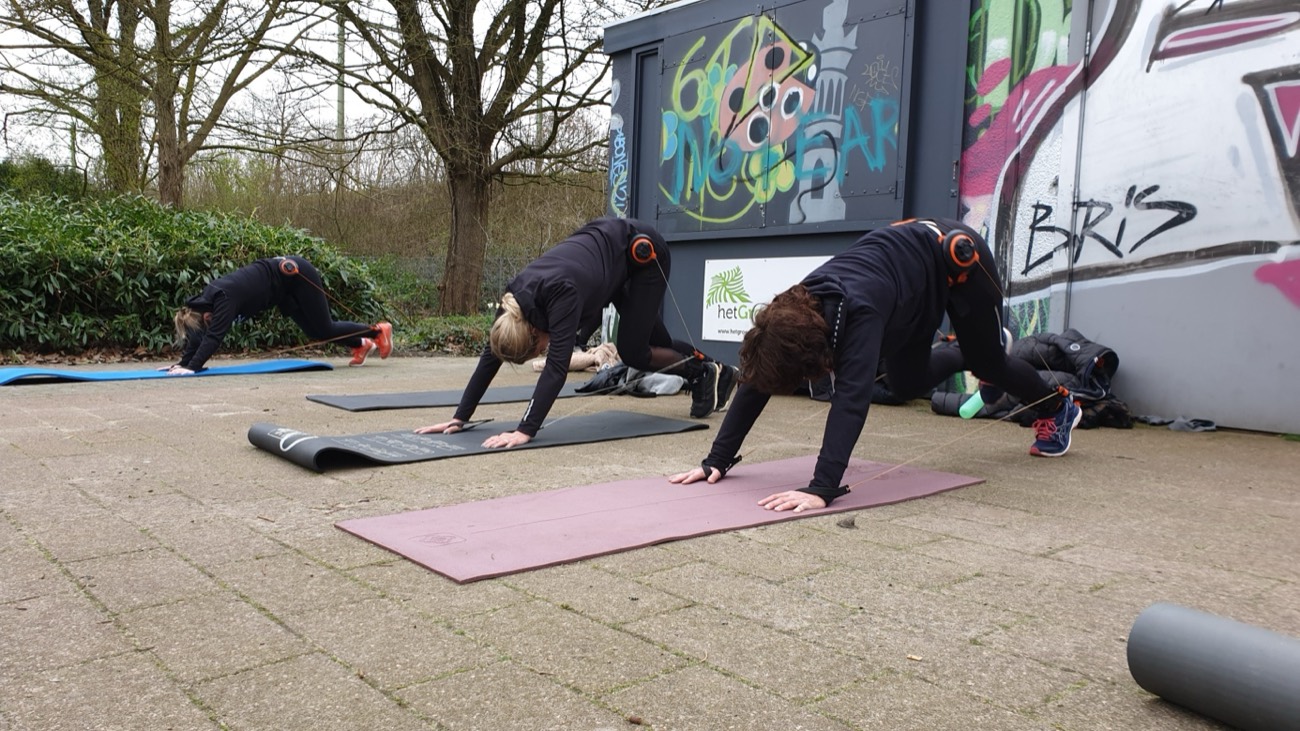 Deelneemsters doen plankoefeningen op matten in het park